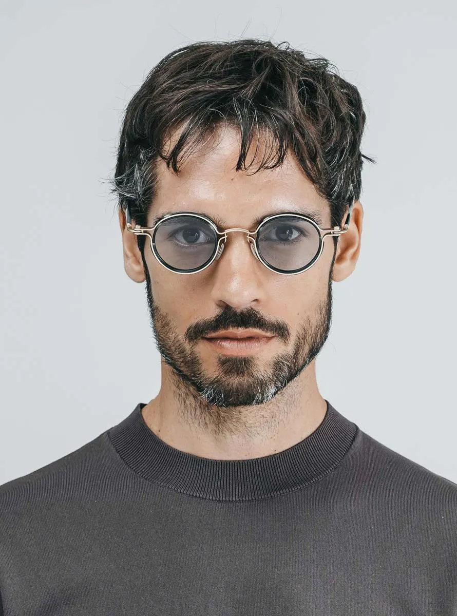 Model wearing Tavat Orb C with gold metal, black eye-rims and grey lenses