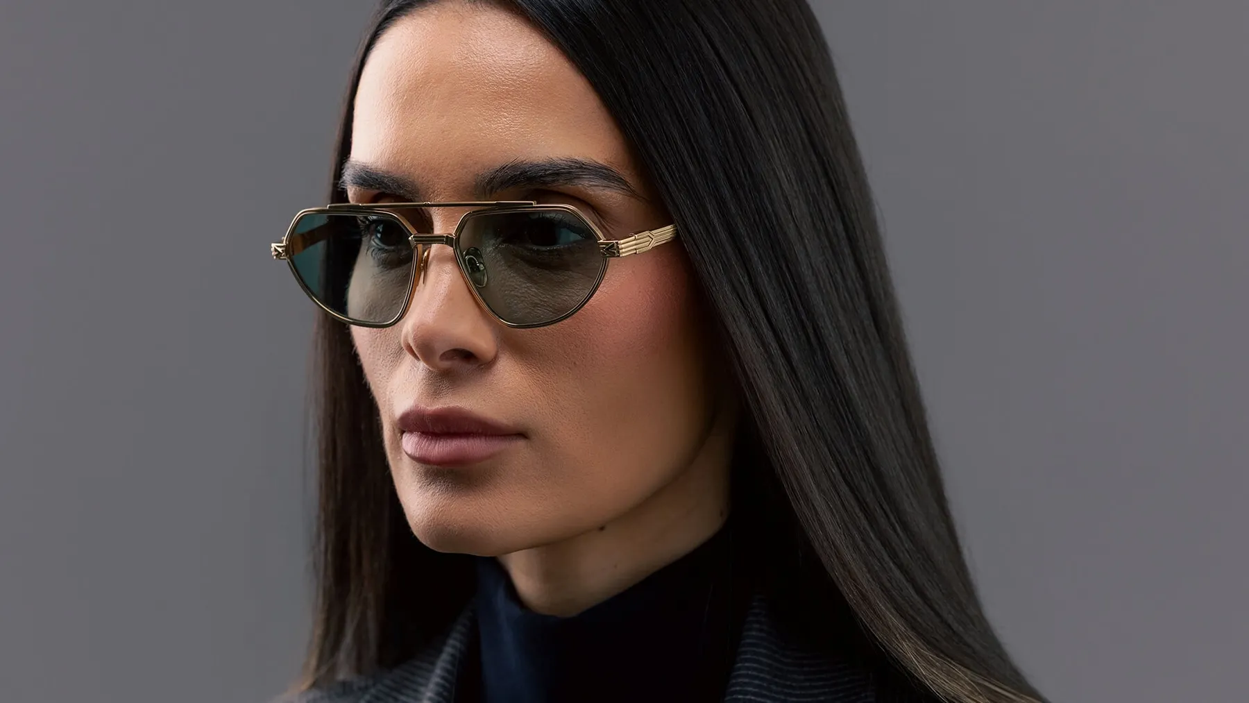 Woman wearing Pray Maya sunglasses, gold frame and green lenses