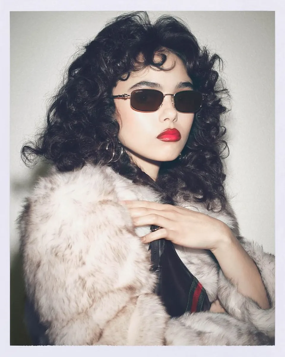 Gucci eyewear campaign, Spring-Summer 2026: a woman with curly hair in a fur coat, wearing sunglasses with a thin gold metal frame